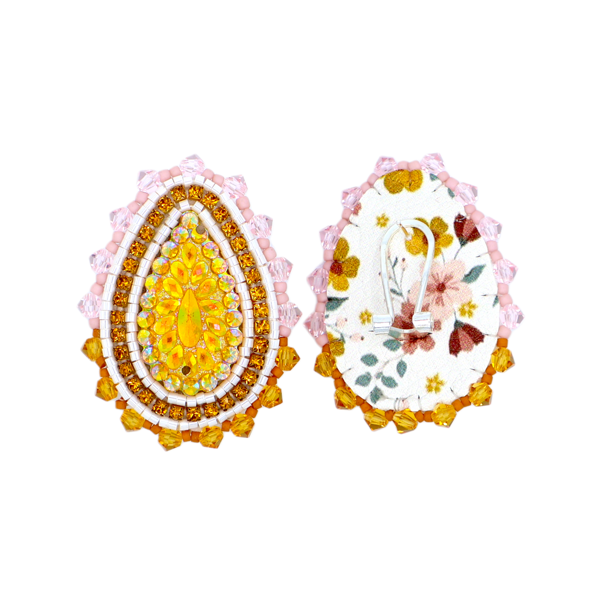 Two decorative teardrop-shaped egg-shaped accessories shown side by side on a plain white background. The left piece is embellished with rows of yellow, orange, and white rhinestones and a pink scalloped border.