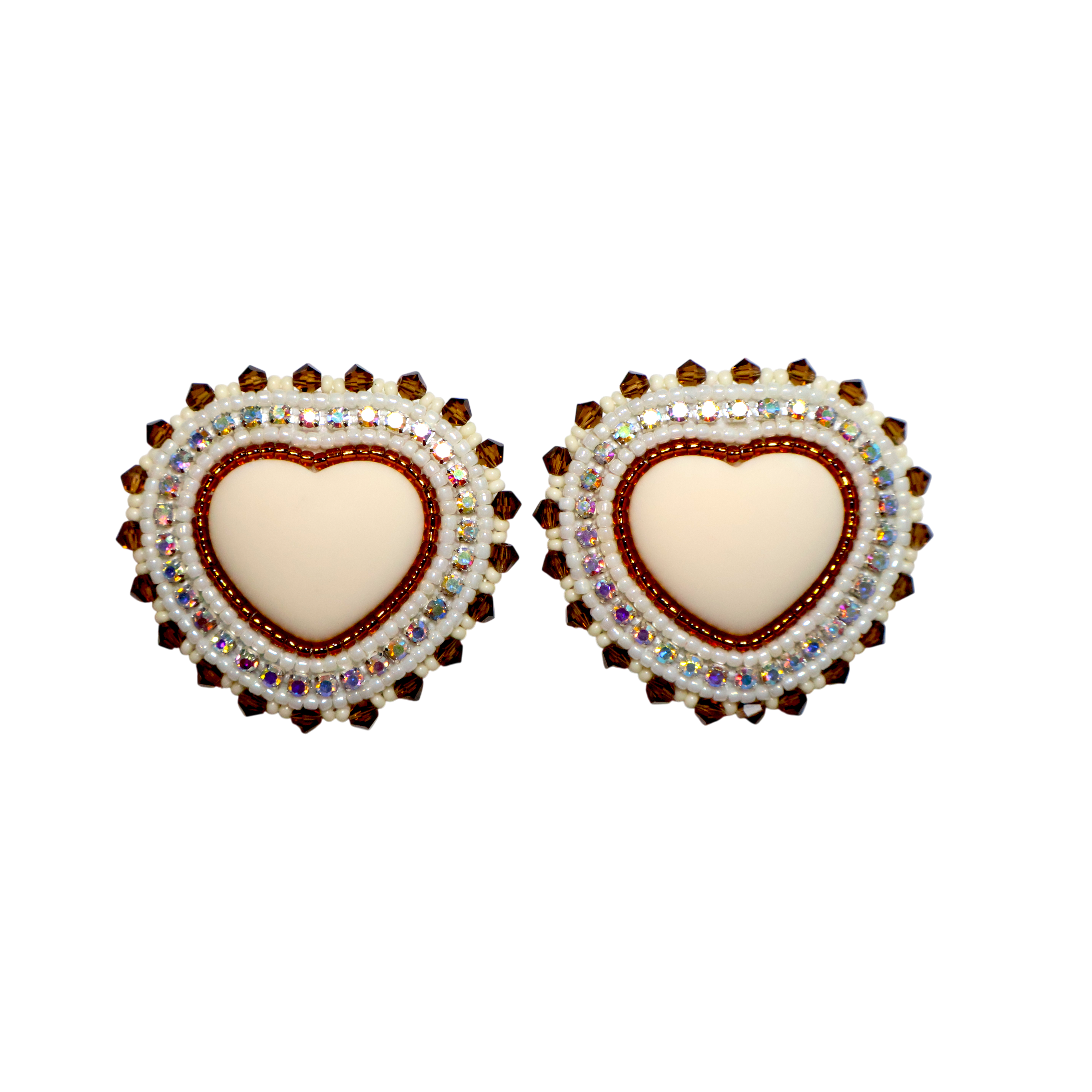 A pair of heart-shaped stud earrings featuring a cream-colored center heart surrounded by a red beaded border and a halo of iridescent rhinestones, set against a plain white background.