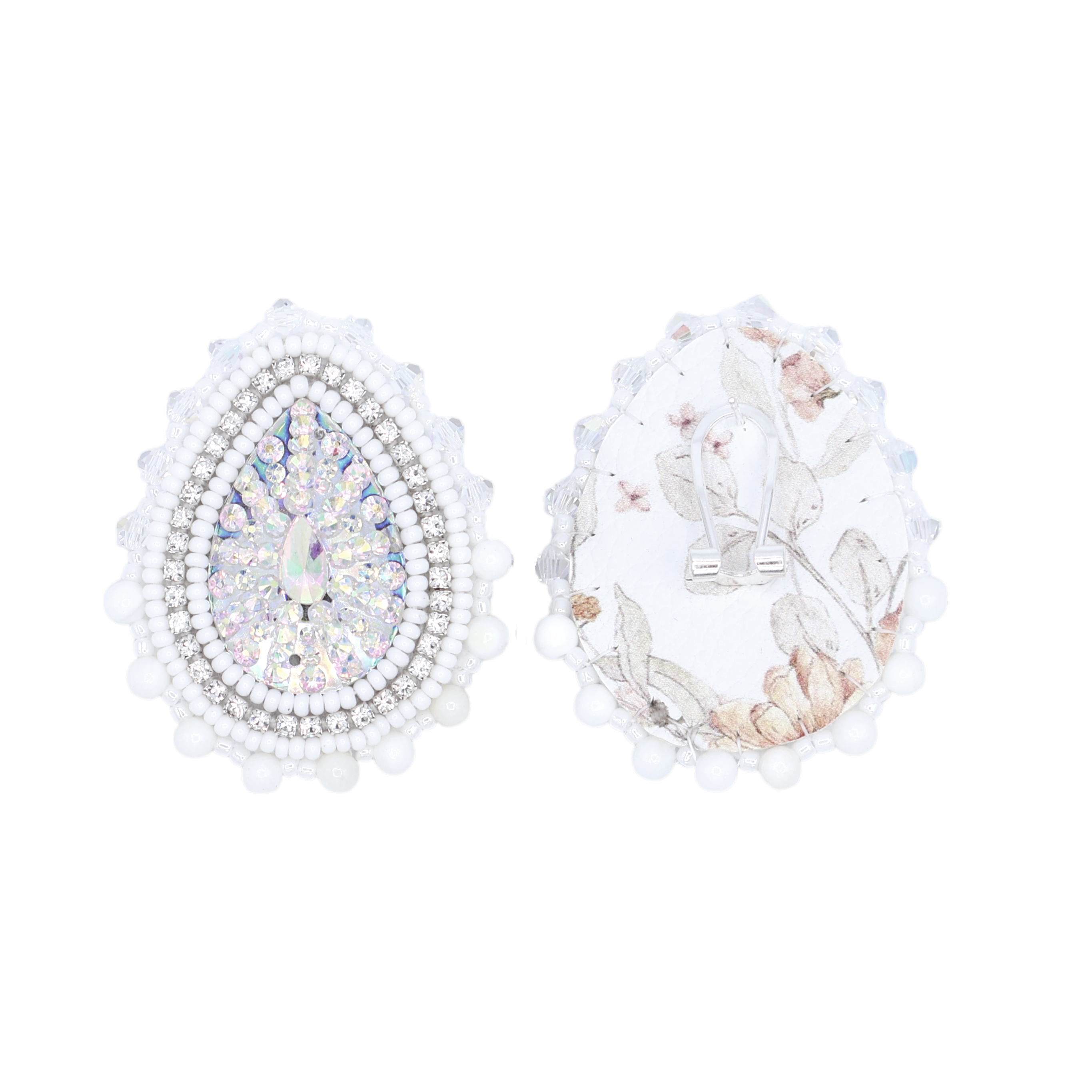 A pair of teardrop-shaped silver earrings with white pearl borders, one decorated with iridescent rhinestones and the other with a white floral print, shown on a plain white background.