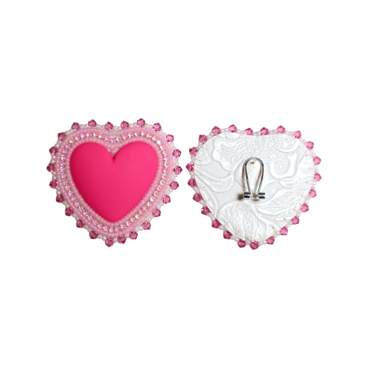 A pair of heart-shaped brooch pins shown from the front and back on a plain white background. The front pin features a bright pink center heart surrounded by a border of pink rhinestones and small pearls.